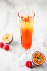 Fresh sparkling berry drink with passion fruits and raspberries in wine glass.
