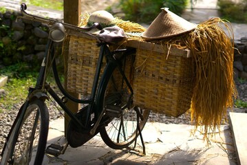 Fototapeta premium old retro bicycle carrying hay from farm on a basket with a farmer cap