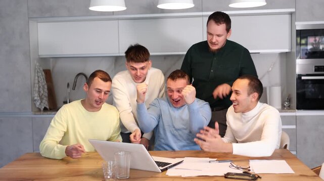 Group of men watching sports match online on laptop during friendly meeting with beer at home, excitedly celebrating winning score in game 