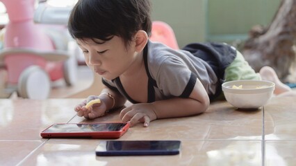 A young boy is laying on the floor with a tablet