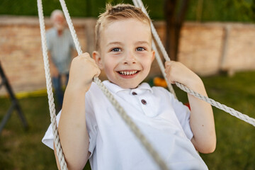 Portrait of child swinging on a swing and smiling at camera.