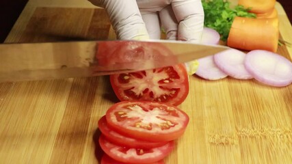 Men hand slices red tomatoes, demonstrating culinary skill. Chef preparing vegetarian meal in the kitchen, 4k footage.
