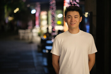 Fototapeta premium Cute Chinese young man smiling, front portrait at night
