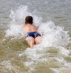 A boy runs through the water of the sea and jumps into the water