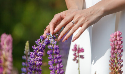 Fototapeta premium A girl touches Lupine flowers in the park with her hands