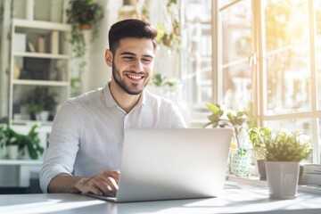 Fototapeta premium High-resolution brightly lit photorealistic candid photograph of a young marketer working on his laptop in a bright, airy office with a joyful expression. The photograph is styled like a high-end