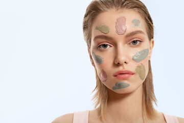 Close up studio portrait of Beautiful young woman with different strokes of clay mask on her face....