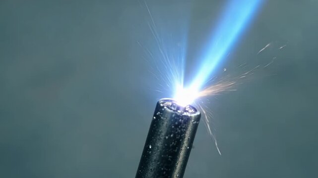 Piezoelectric lighter is generating a blue jet flame with sparks flying in the air. The image evokes concepts such as danger, fire, energy, and combustion