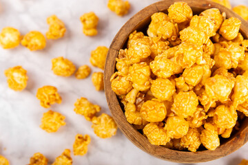 Sweet caramel popcorn in a bowl on a wooden background. Salted caramel popcorn. Caramel sauce. Close up. Topping. Place for text. Copy space