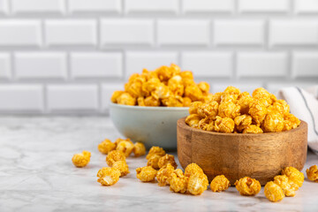 Sweet caramel popcorn in a bowl on a wooden background. Salted caramel popcorn. Caramel sauce. Close up. Topping. Place for text. Copy space