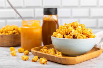 Sweet caramel popcorn in a bowl on a wooden background. Salted caramel popcorn. Caramel sauce. Close up. Topping. Place for text. Copy space