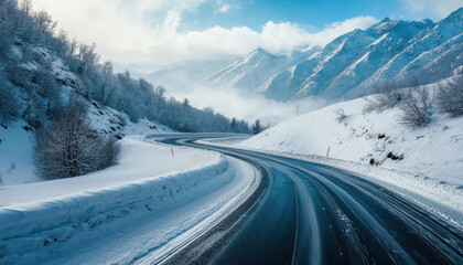 Black car driving on a winding snowy road in the mountains.