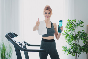 Photo of active energetic healthy woman wearing sportswear running treadmill physical exercises home gym indoors thumb up