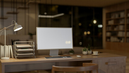 A computer mockup on a wooden table in a living room at night, illuminated by a table lamp.