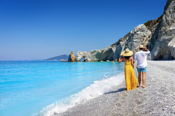 A summer tourist couple walks down the beautiful beach of Lalaria at Skiathos island, Sporades,...