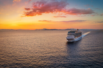 Aerial view of a generic cruise ship traveling over the ocean during golden summer sunset time with...