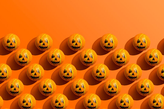 Pattern of rows of Halloween candy with jack o lantern wrapping against orange background