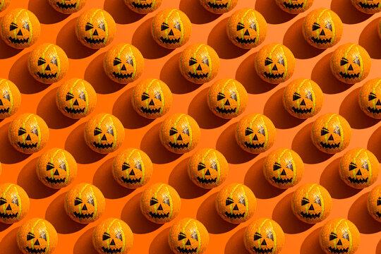 Pattern of rows of Halloween candy with jack o lantern wrapping against orange background