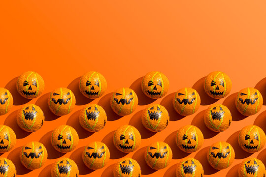 Pattern of rows of Halloween candy with jack o lantern wrapping against orange background