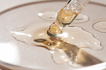 Bottle pipette dropper close up and Liquid yellow-orange retinol or vitamin c gel or serum on a...