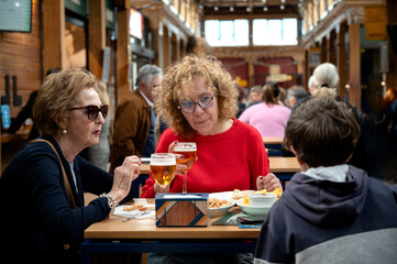 Three generations family enjoying a meal and drinks at a crowded indoor market