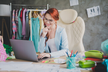 Photo of thoughtful girl shop assistant sit table use netbook for online selling products in...