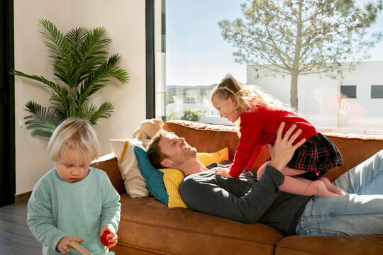 Smiling father spending leisure time with kids in living room at home