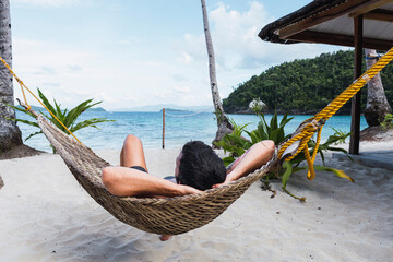 Man lying on hammock at beach near sea