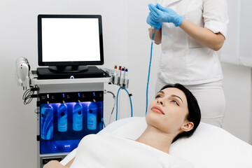 A cosmetologist wearing gloves performs vacuum cleaning and polishing of the facial skin of a...