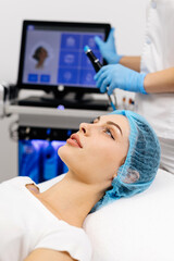 A cosmetologist wearing gloves performs vacuum cleaning and polishing of the facial skin of a middle-aged woman in a cosmetology clinic. Professional moisturizing and rejuvenating hardware procedures.