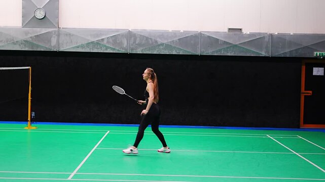 Sports young woman with racket and shuttlecock is exercising, playing in badminton on inside court