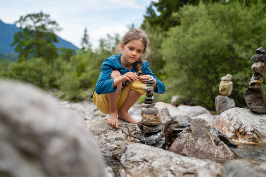 Girl stacking rocks near forest