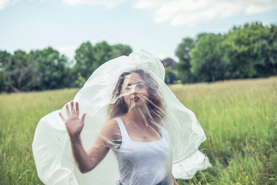 Young woman wrapped in polythene on field