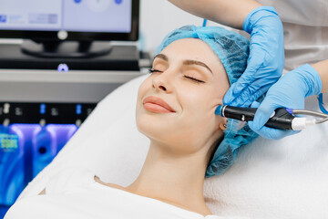 A cosmetologist wearing gloves performs vacuum cleaning and polishing of the facial skin of a...