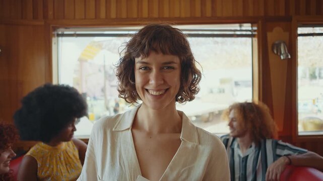 Cinematic footage about a group of multi-ethnic friends eating and having fun in an american styled diner restaurant.Beautiful woman smiling to camera.