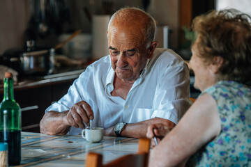 Family life of a senior couple at home drinking coffee