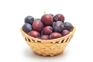 A basket of ripe plums on a white background, close-up. Homemade organic fruits