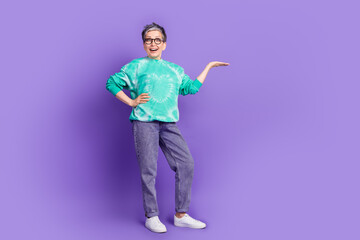 Full length photo of lovely pensioner lady hold empty space dressed stylish green garment isolated on purple color background