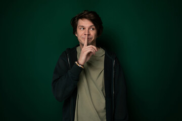 Man Standing in Front of Green Wall With Finger in Mouth