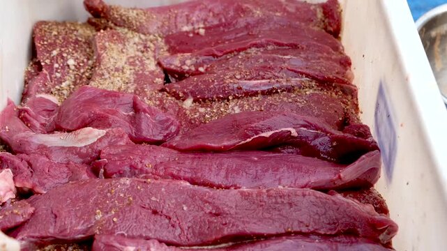 Closeup of quality venison steaks stacked and spiced with mixed herbs and vinegar to cure and preserve meat to make traditional biltong South African jerky