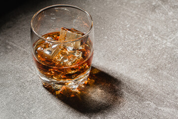 Glass of whiskey with ice on a light background