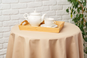 White Teapot and Cup on Wooden Tray on Tan Tablecloth