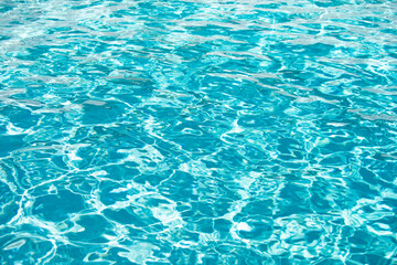 Water background. Blue water, ripples and highlights. Texture of water surface and tiled bottom.