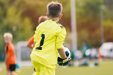 Young boy as a soccer goalie holding the ball in one hand ready to start a game. Football...