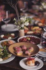Brunch table setting with different delicious food and beverages ready for friends home party. A variety of food on the table, fish, olives, bread, raspberries, meat. 