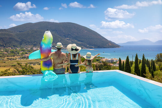 Travel concept with children with a summer holiday family sitting on the edge of a swimming pool and enjoying the view