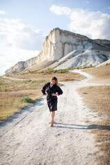 A woman plus size dressed in a dress walking against the background of a white mountain. Beautiful girl with a long hair developing in the wind travels