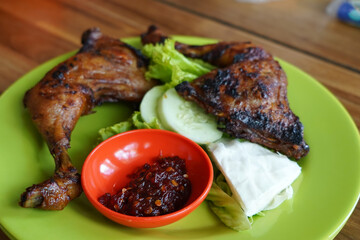 Two grilled chicken legs served on a green plate