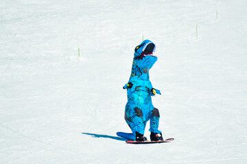 Gudauri, Georgia - 15th february, 2024: front view skier wear blue dinosaur costume snowboard...