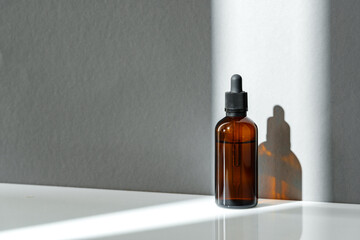 Amber Glass Dropper Bottle With Sunlight Shadow on White Surface